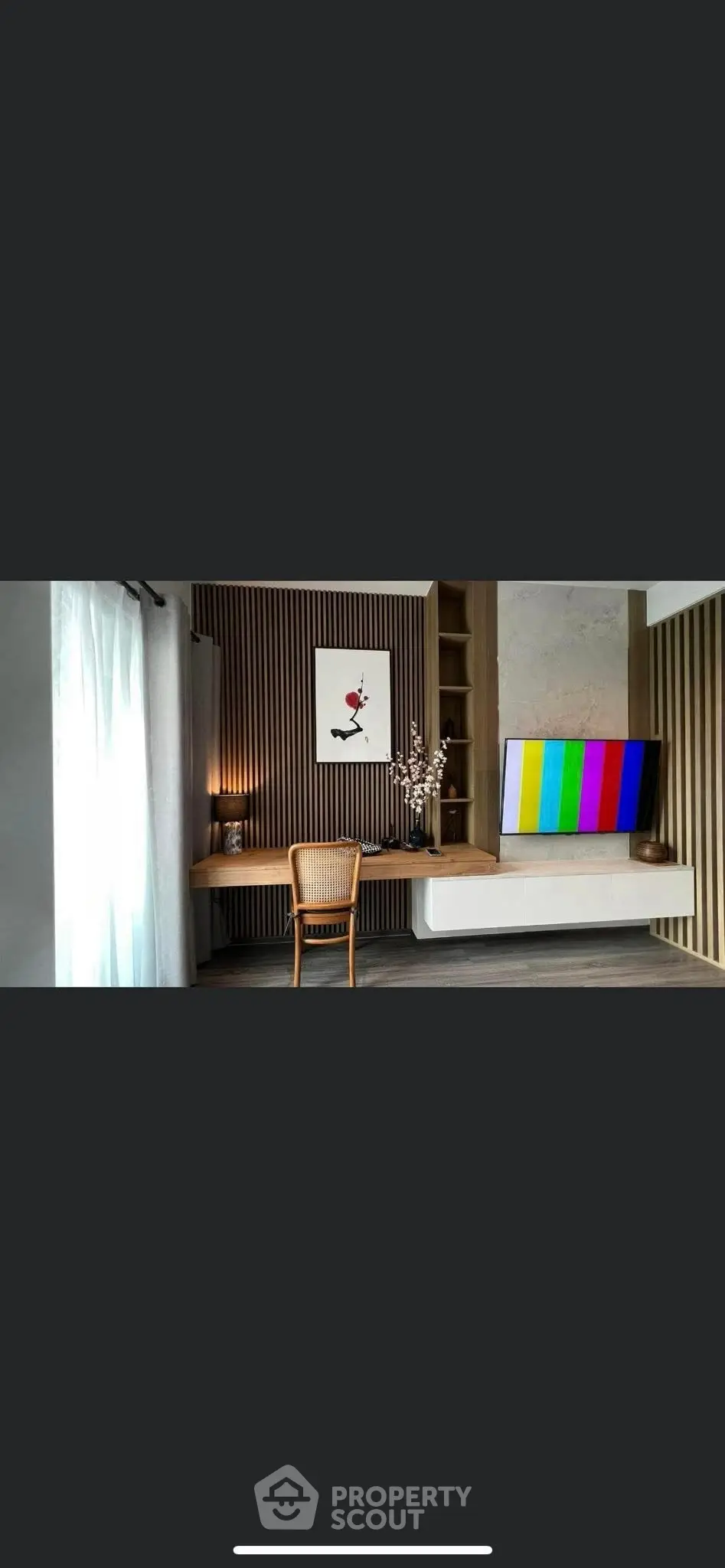 Modern living room with stylish decor and wall-mounted TV, featuring a cozy workspace and elegant lighting.