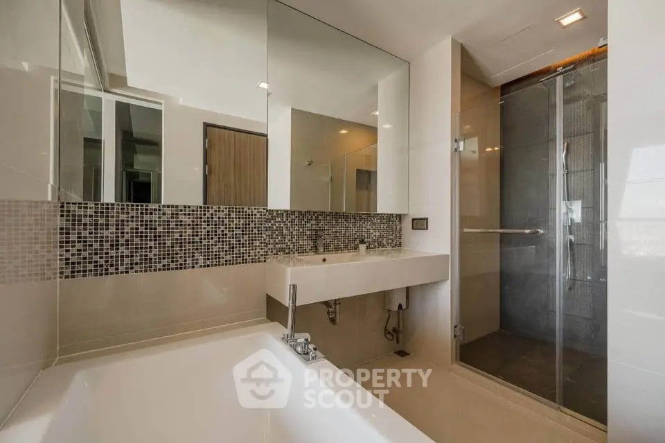 Modern bathroom with sleek design, featuring a bathtub and glass-enclosed shower.