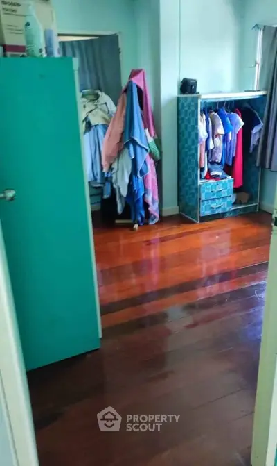 Charming bedroom with wooden floors and open wardrobe, perfect for cozy living.