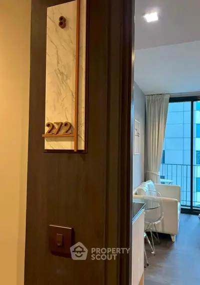 Modern apartment entrance with view into stylish living room and balcony access.