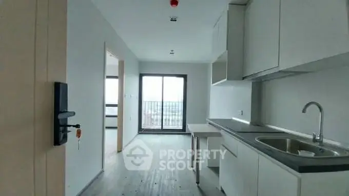 Modern kitchen with sleek cabinetry and balcony view in a bright apartment.