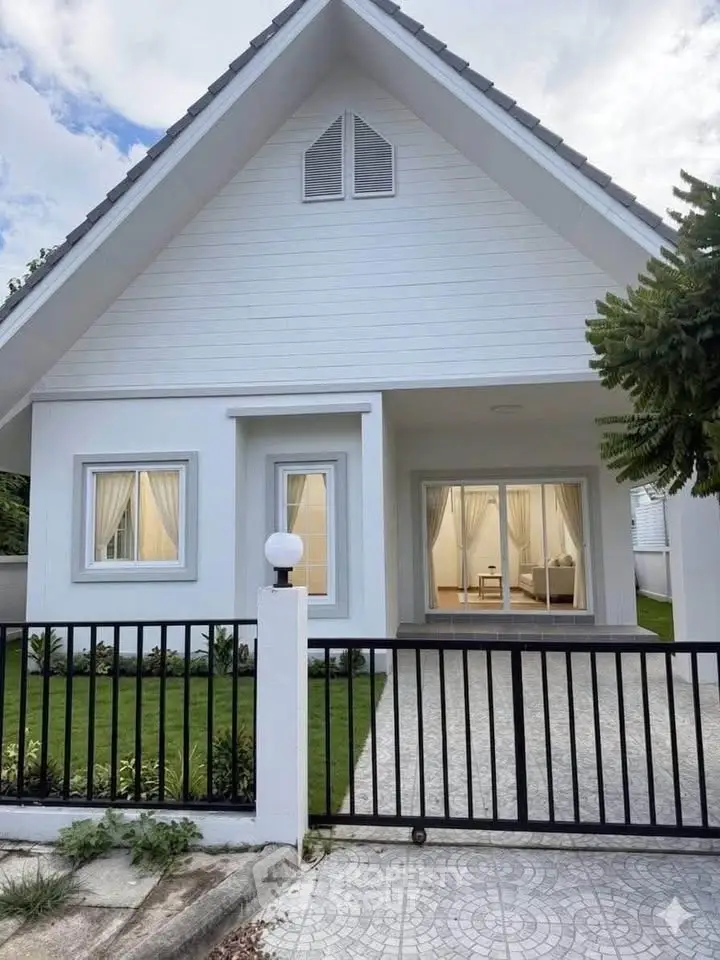 Charming modern white house with pitched roof and inviting front yard, perfect for family living.