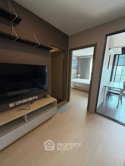 Modern apartment interior with living room and bedroom view, featuring sleek furniture and natural light.
