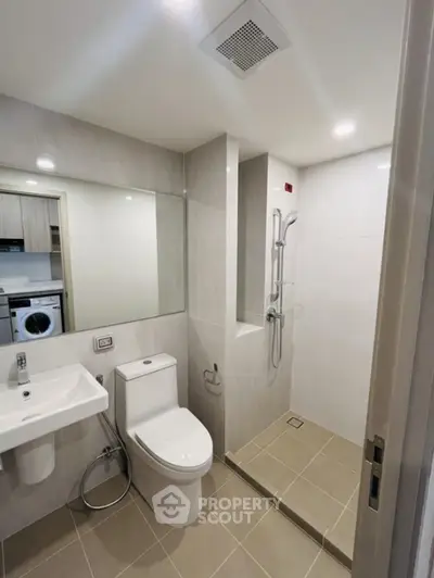 Modern bathroom with shower and washing machine in sleek apartment