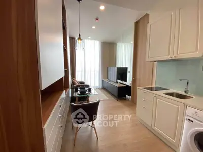 Modern living room with open kitchen, featuring sleek cabinetry and a washing machine, perfect for urban living.