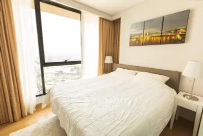 Bright and cozy bedroom with large window offering stunning city views, perfect for relaxation.