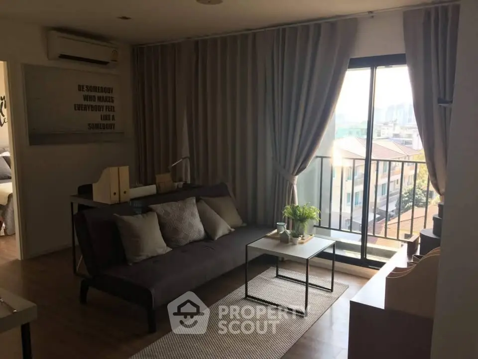 Cozy living room with balcony view, modern decor, and ample natural light in urban apartment.