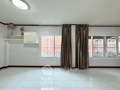 Spacious unfurnished room with large windows and elegant curtains, perfect for customization.