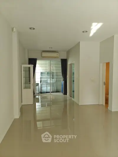 Spacious modern living room with glossy tiled floors and large windows.