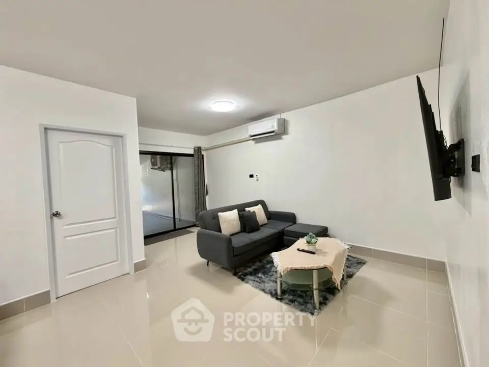 Modern living room with sleek sofa and wall-mounted TV in minimalist design.