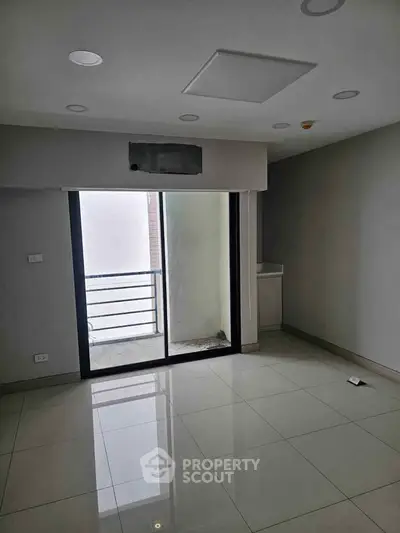 Spacious modern room with large sliding glass doors leading to a balcony, perfect for natural light.
