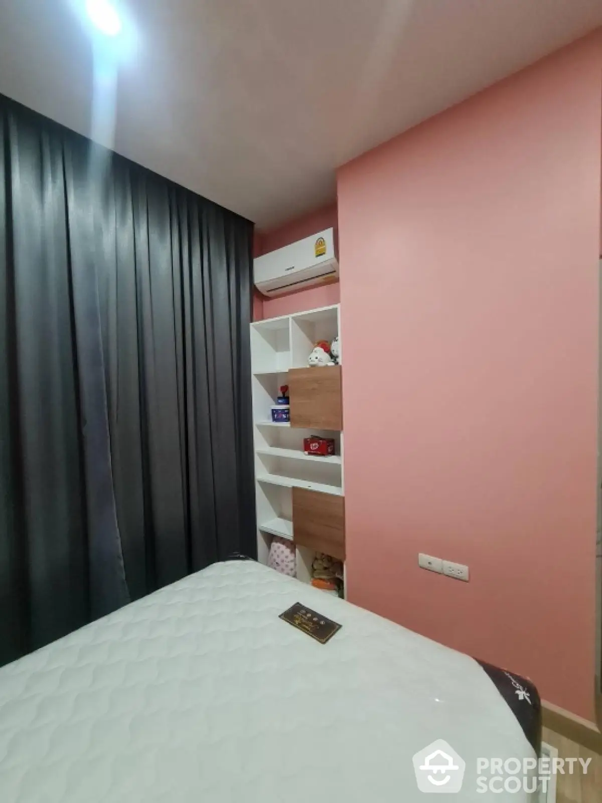 Cozy bedroom with modern decor, featuring a built-in shelf and air conditioning unit.