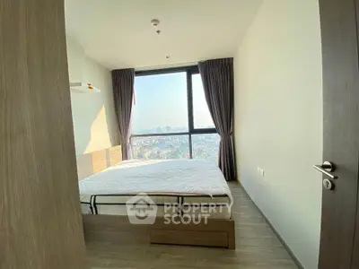 Modern bedroom with large window offering stunning city views and natural light.