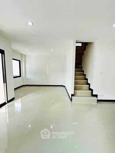 Spacious modern living room with sleek staircase and glossy tiled floors