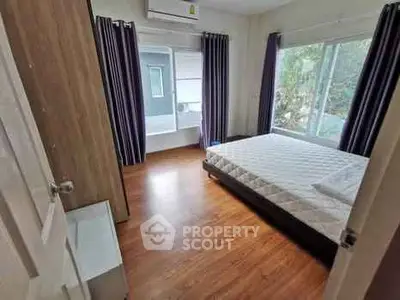 Spacious bedroom with large windows and wooden flooring