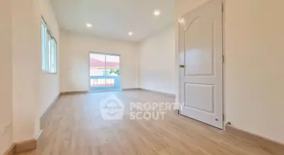 Spacious empty room with wooden flooring and balcony access, ideal for customization.