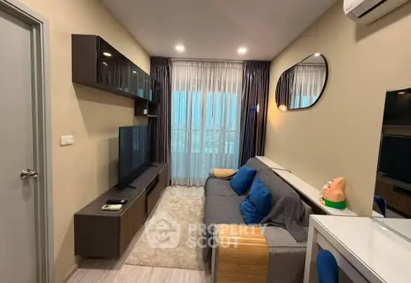 Modern living room with sleek furniture and large TV, featuring stylish decor and natural light.