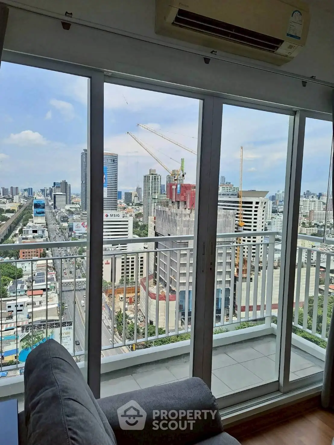 Stunning city view from modern apartment balcony with floor-to-ceiling windows.