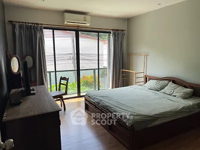 Cozy bedroom with large window and wooden furniture, perfect for relaxation and comfort.