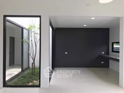 Modern minimalist interior with large windows and sleek design, featuring a small indoor garden.