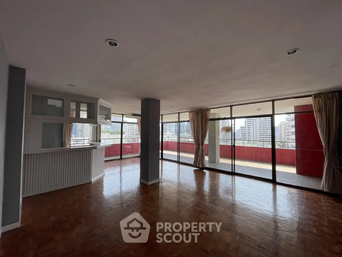 Spacious living room with large windows and city view, featuring a big balcony for outdoor enjoyment.