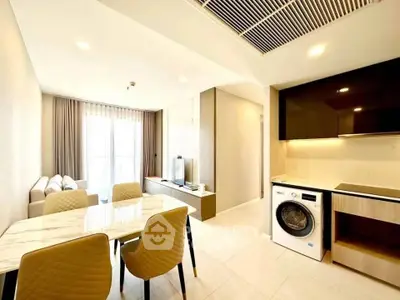 Modern open-plan living room and kitchen with dining area and washing machine.