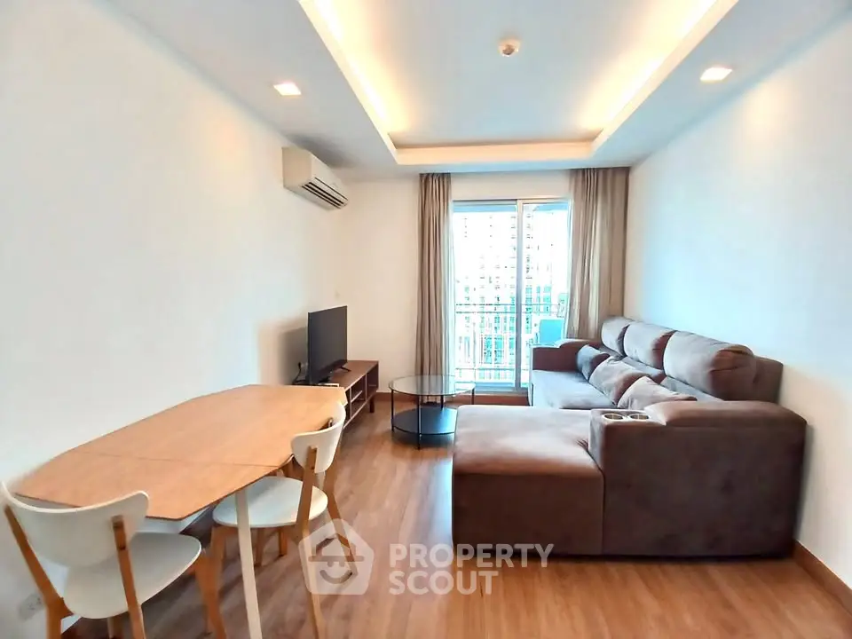 Modern living room with cozy sectional sofa and dining area, featuring a bright balcony view.