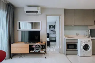 Modern living room with TV, washing machine, and sleek kitchen in stylish apartment.