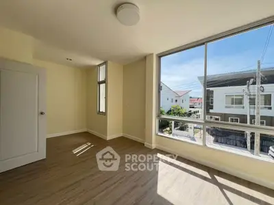 Bright empty room with large windows and wooden flooring, perfect for a cozy living space.