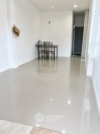 Spacious minimalist dining area with sleek tiled flooring and modern furniture.
