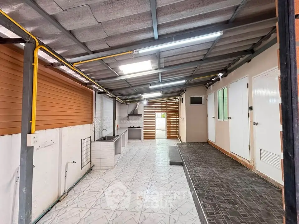 Spacious covered outdoor area with tiled flooring and modern lighting, perfect for versatile use.