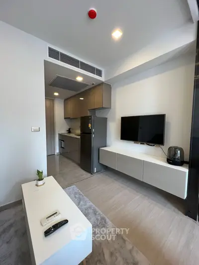 Modern living room with sleek kitchen and wall-mounted TV in open layout apartment.