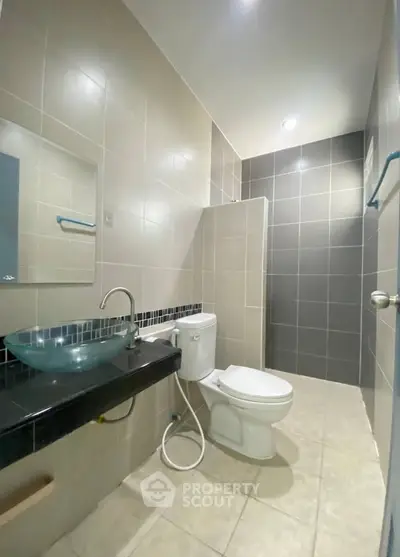 Modern bathroom with sleek glass sink and tiled shower area