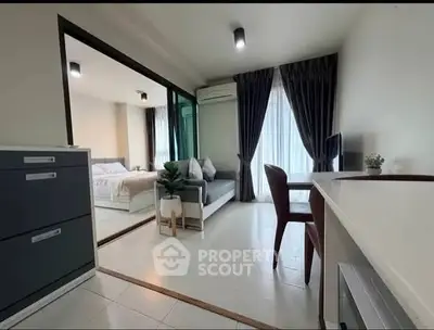 Modern apartment interior with open living room and bedroom, featuring sleek furniture and natural light.