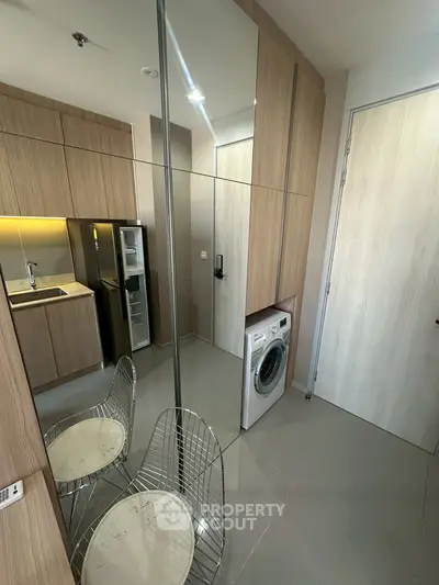 Modern kitchen with sleek cabinetry and built-in washing machine in compact apartment.