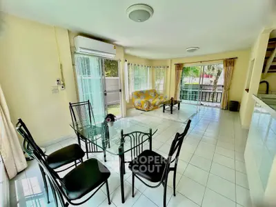 Spacious living room with glass dining table and garden view, perfect for family gatherings.