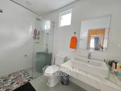 Modern bathroom with glass shower, white tiles, and sleek fixtures.