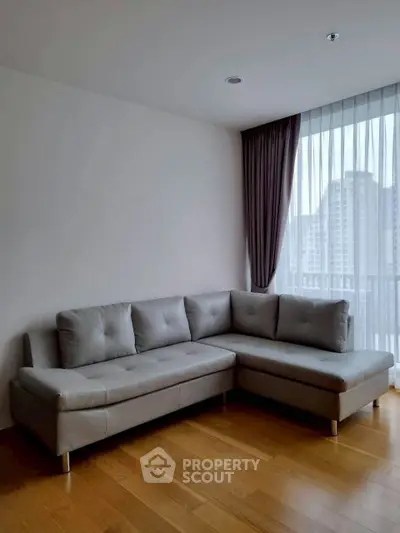 Modern living room with stylish L-shaped sofa and city view through large window.