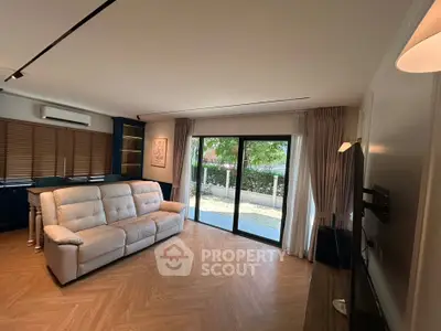 Spacious living room with modern decor and large windows opening to a garden view.