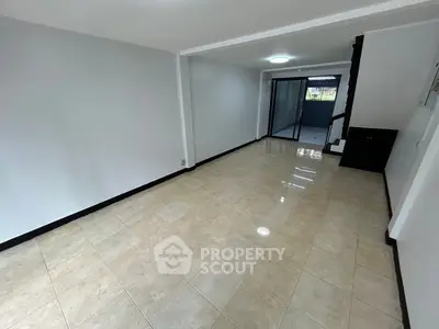 Spacious tiled living room with sliding glass doors leading to a balcony, perfect for modern living.