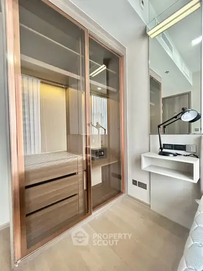 Modern bedroom with built-in wardrobe and sleek desk lamp, showcasing contemporary design and functionality.