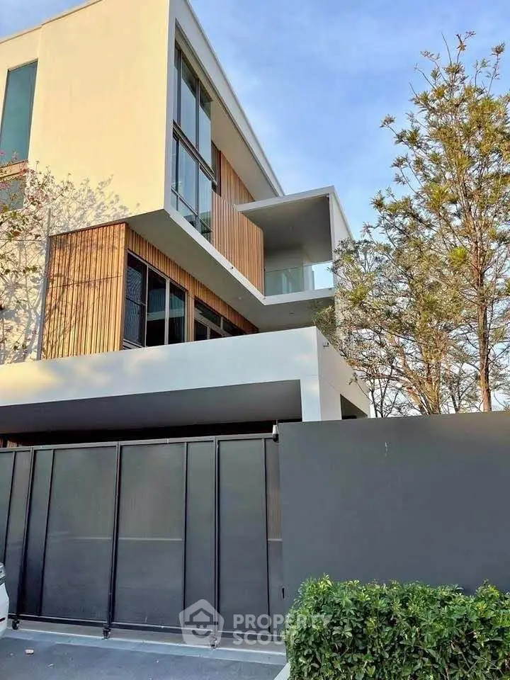 Modern architectural home with sleek design and spacious balcony, surrounded by lush greenery.