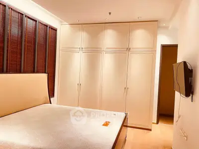 Spacious bedroom with built-in wardrobe and wall-mounted TV, perfect for modern living.