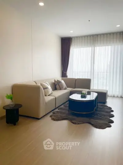 Modern living room with stylish beige sofa and floor-to-ceiling windows in a bright apartment.