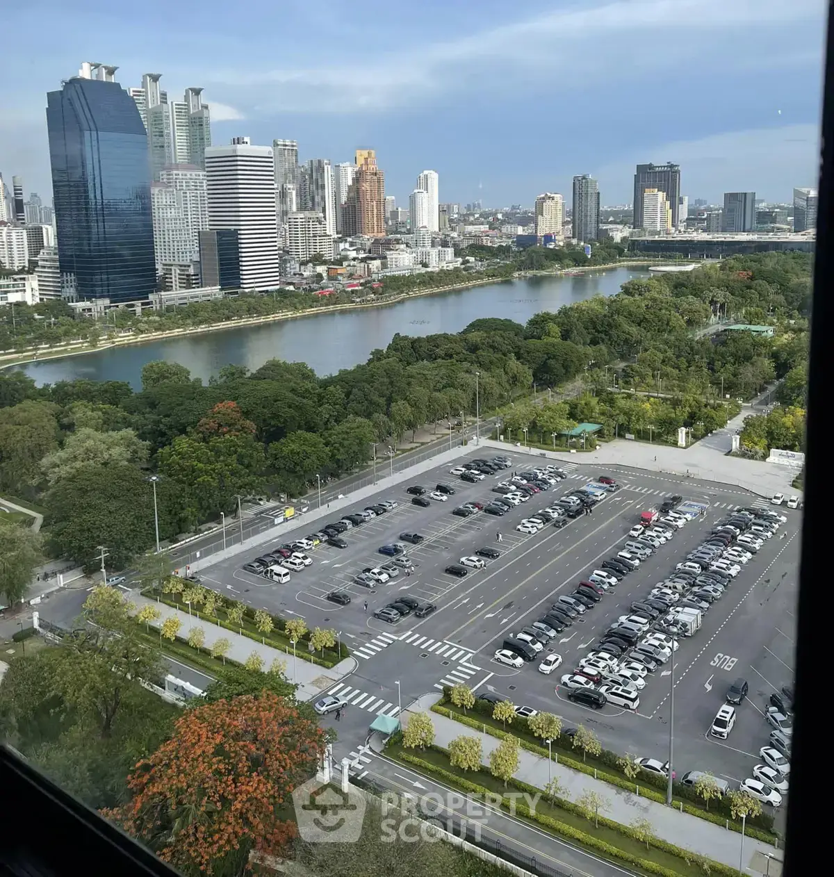 Stunning cityscape view with river and skyline from high-rise building, overlooking spacious parking area.
