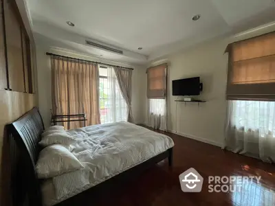 Spacious bedroom with polished hardwood floors, ample natural light, and modern amenities, perfect for relaxation and comfort.