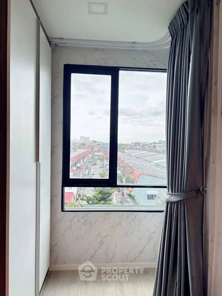 Bright room with large window offering city view, elegant curtains, and modern decor.