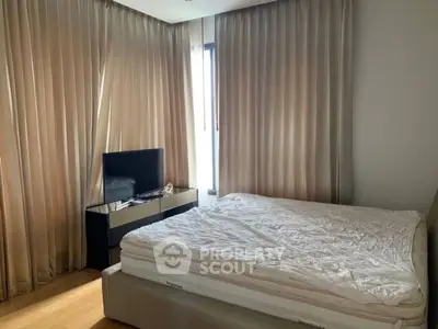 Cozy bedroom with modern TV setup and elegant curtains