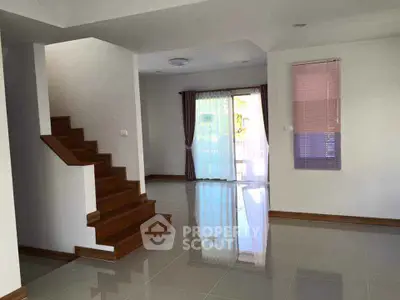 Spacious modern living room with wooden staircase and large windows for natural light.