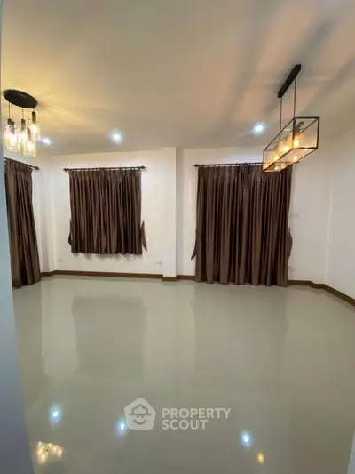 Spacious empty room with elegant lighting and floor-to-ceiling curtains, perfect for customization.